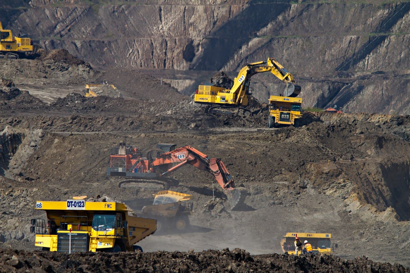 Excavators loading haul trucks on the terraced benches of an open-pit mine